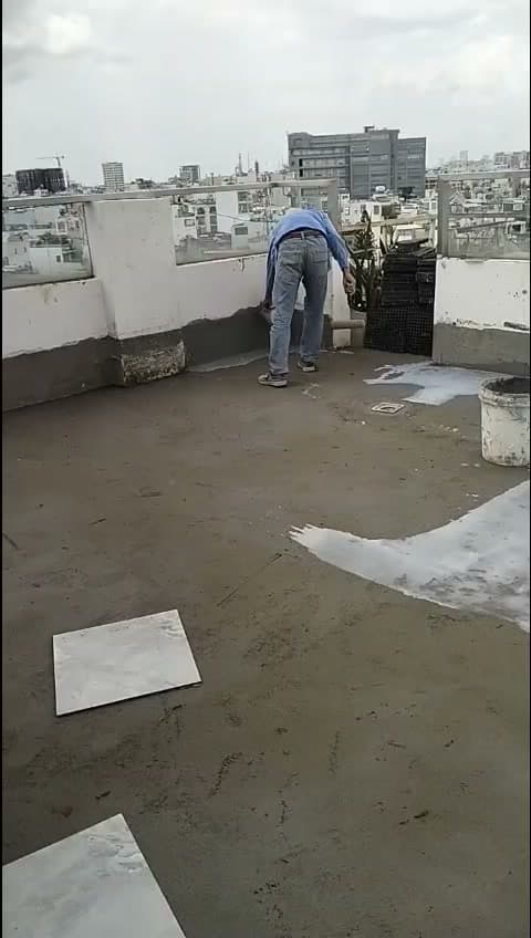 Chân tường sân thượng đã quét chống thấm gốc xi măng, thợ đang xử lý tiếp góc tiếp giáp sàn