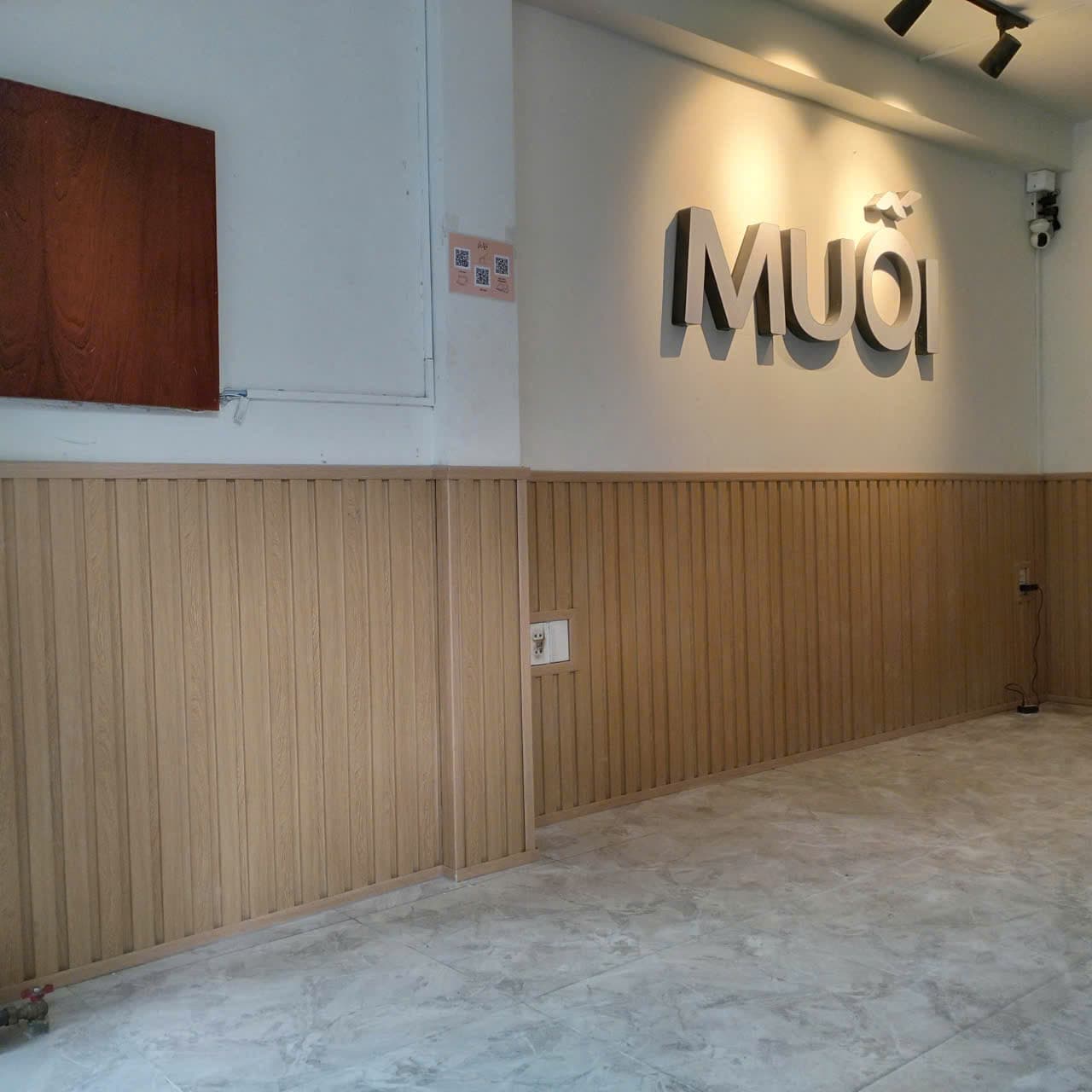 Không gian quán sau khi sửa: tường sơn mới, chân tường ốp lam sóng giả gỗ chạy liền một dải