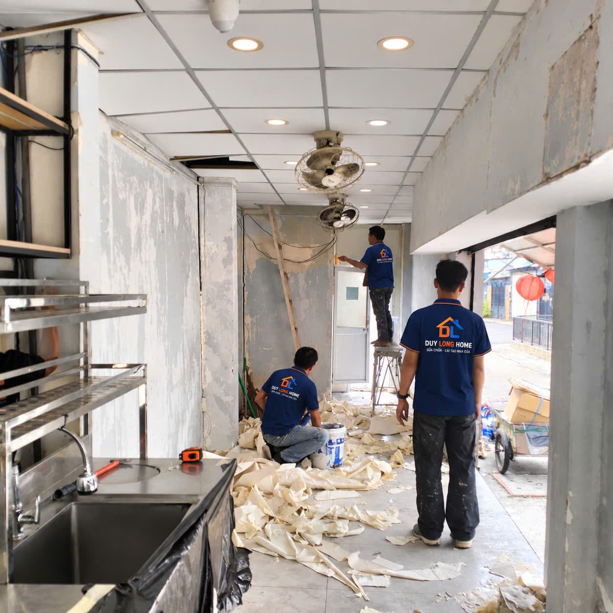 Đội thợ bóc lớp giấy dán tường cũ đã bong, ố trên toàn bộ mảng tường